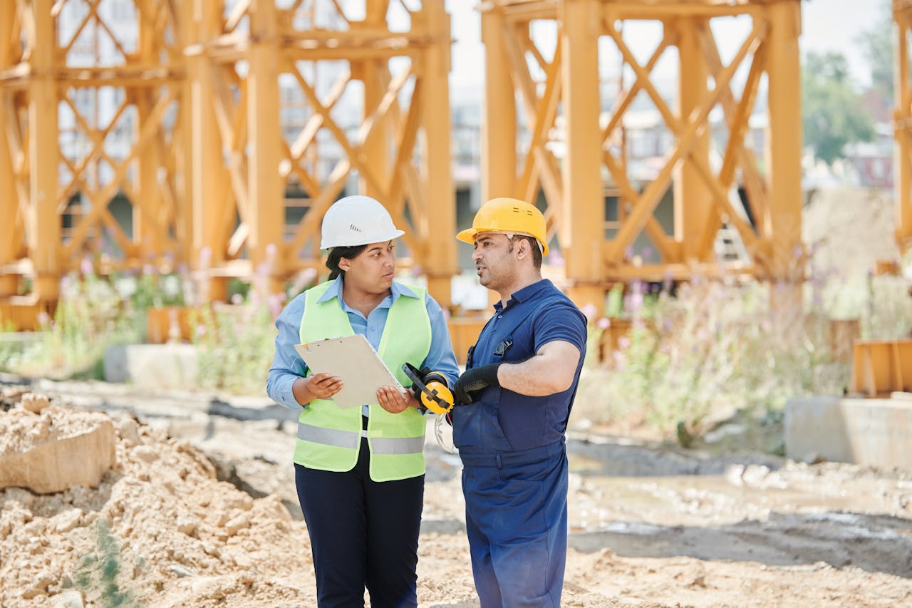 Construction workers engaged in a discussion at a construction site wearing safety gear.